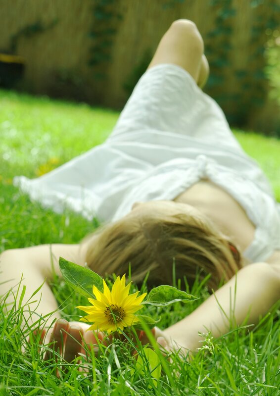 Woman resting in grass with flower