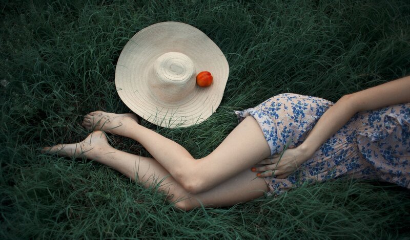 Woman resting in grass with hat