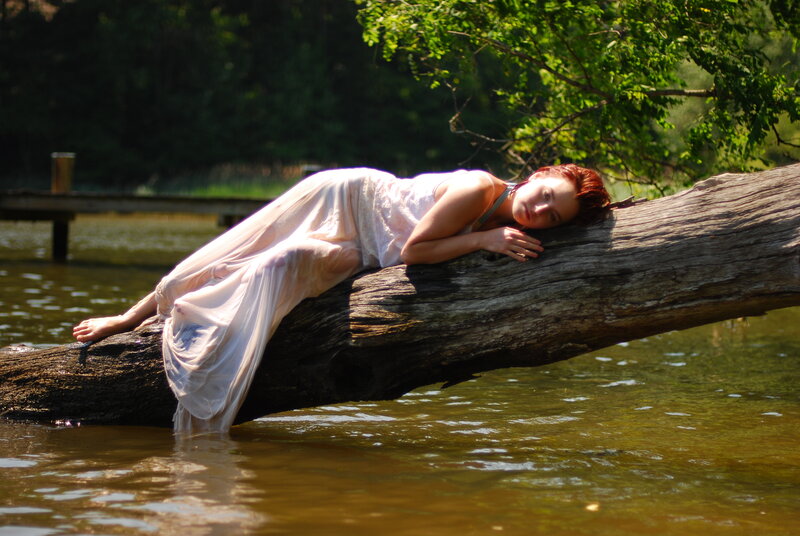 Woman resting on a log in water