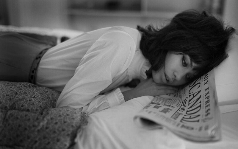 woman resting on bed with newspaper