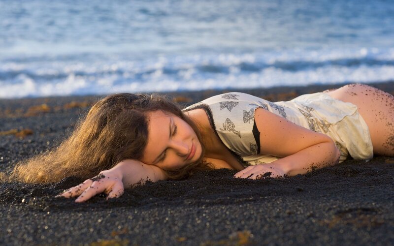 Woman resting on black sand beach
