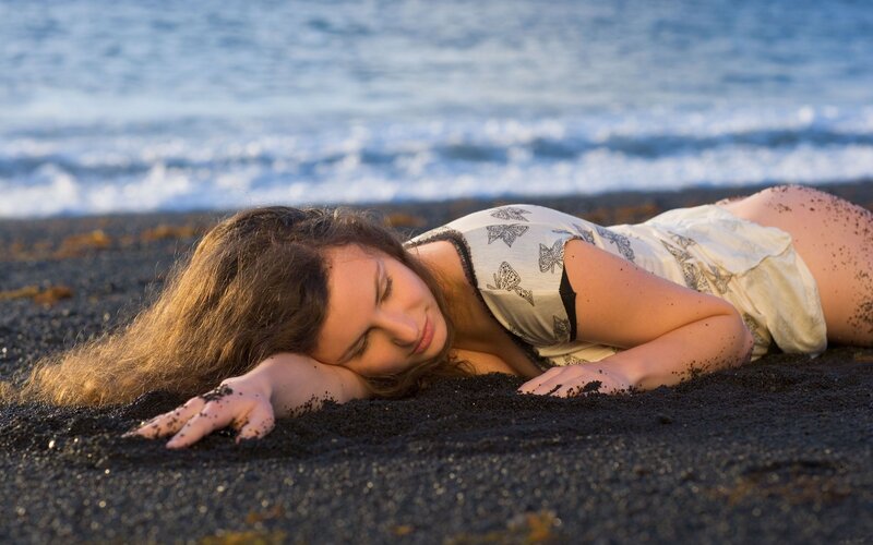Woman resting on black sand beach