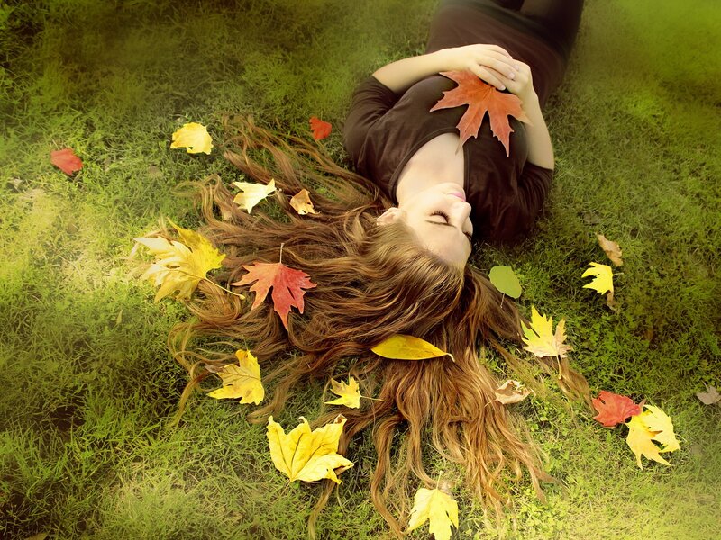 Woman resting on grass with autumn leaves