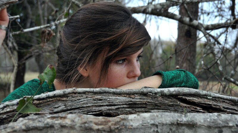 woman resting on log in woods
