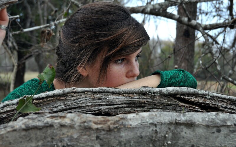 woman resting on log in woods
