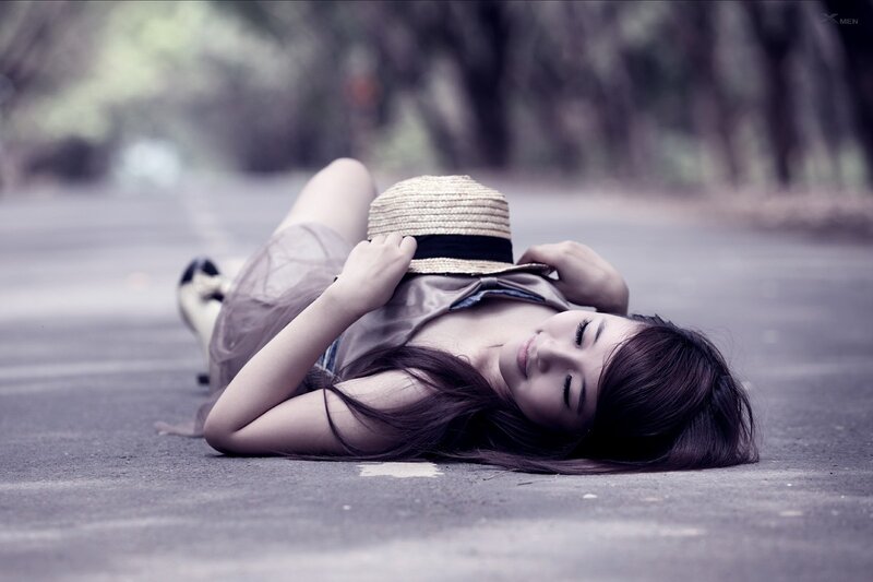 Woman resting on road with hat