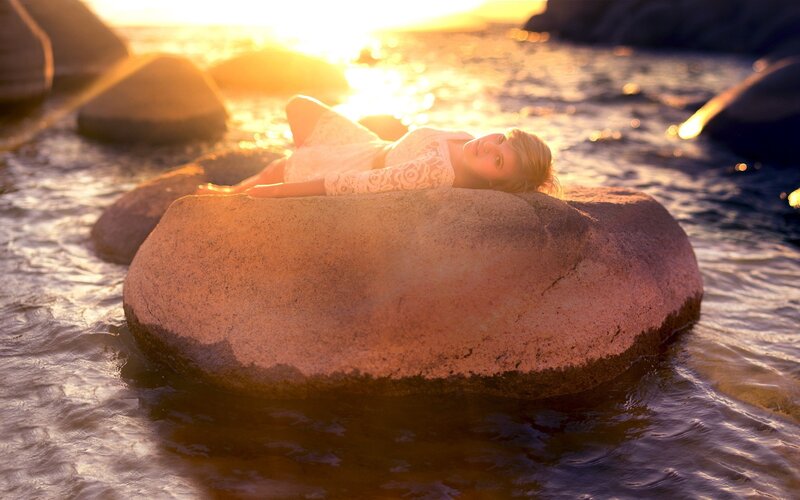 woman resting on rock at sunset