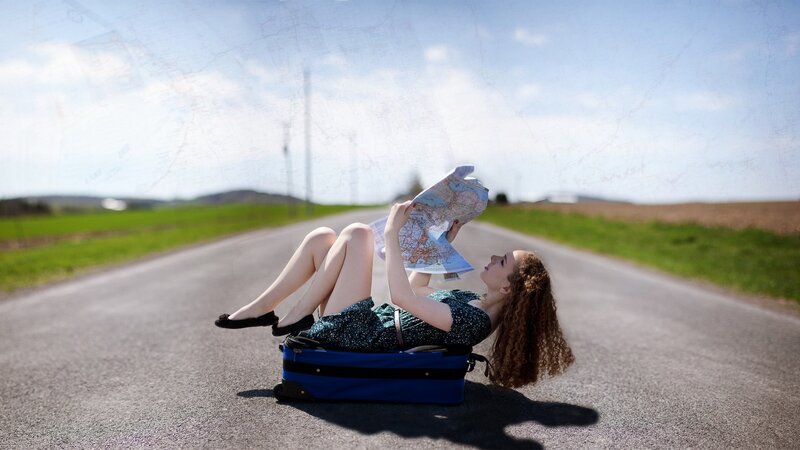 Woman resting on suitcase with map