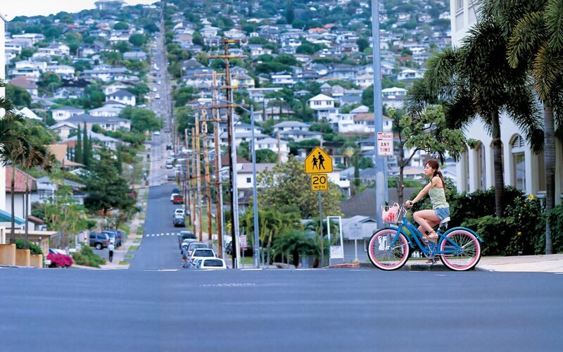 Woman riding bicycle on hillside street