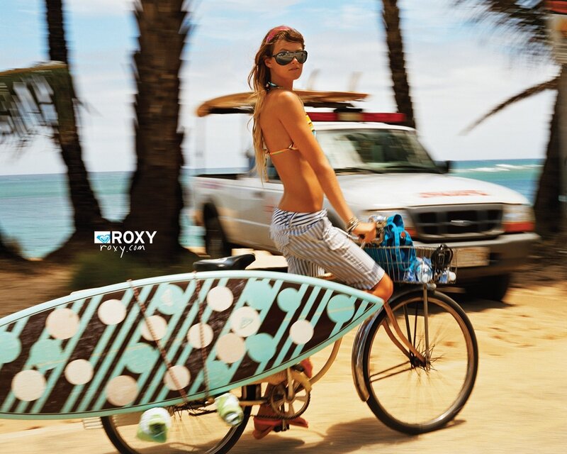 Woman riding bike with surfboard