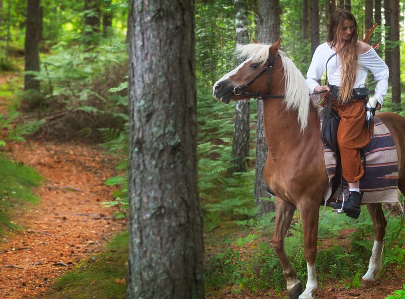 Woman riding horse in forest