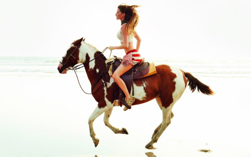 Woman riding horse on beach