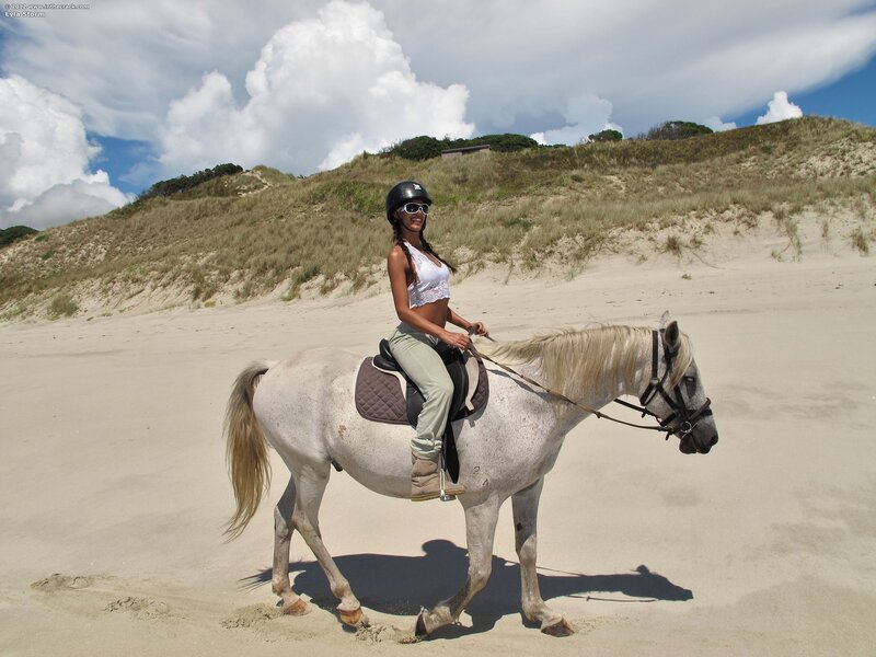 Woman riding horse on beach