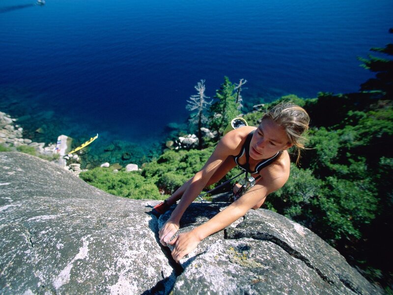 Woman rock climbing by a lake