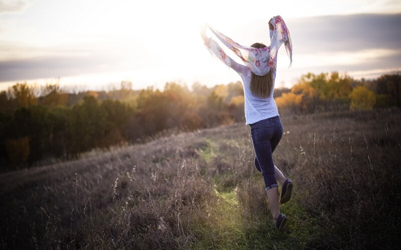 woman running in field at sunset