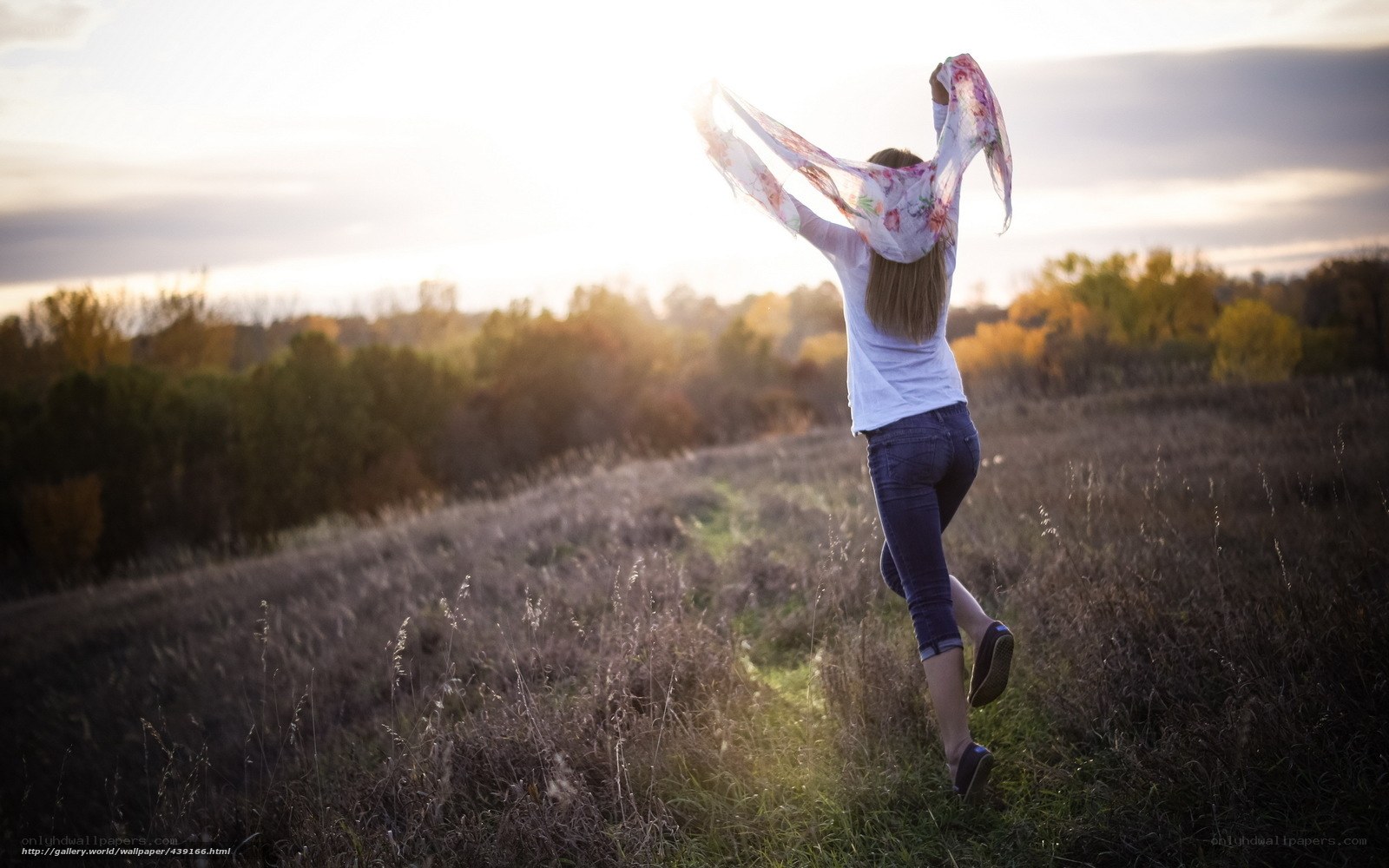 woman running in field at sunset