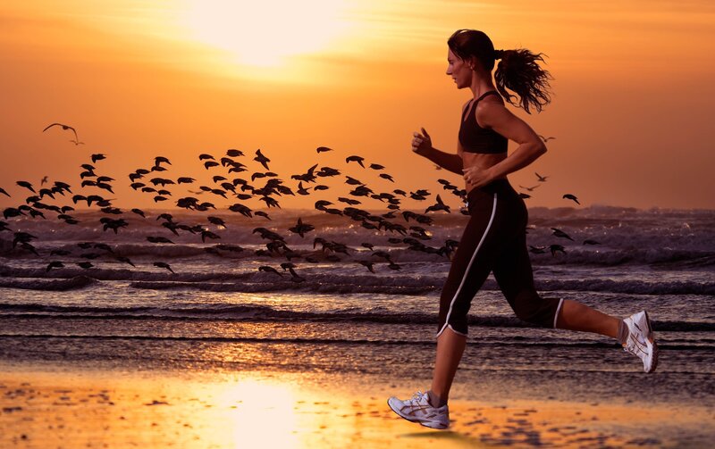 woman running on beach at sunset