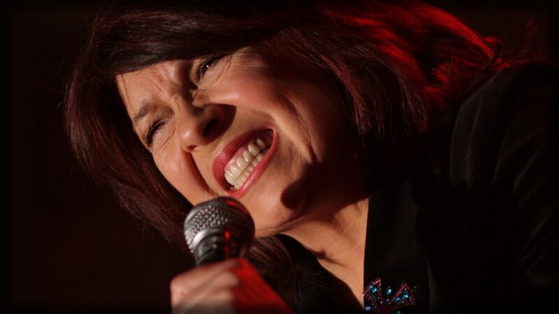 Woman Singing into Microphone — Black, Dramatic, Night, Photograph, Hair