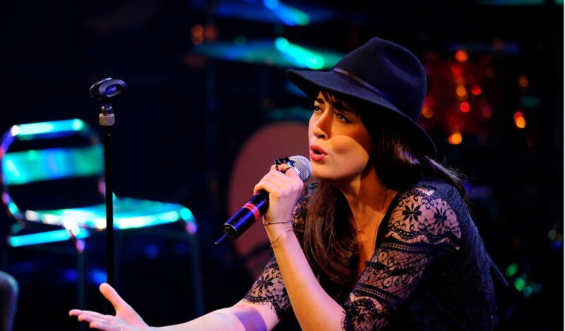 Woman Singing into Microphone — Black, Dramatic, Night, Photograph, Hat