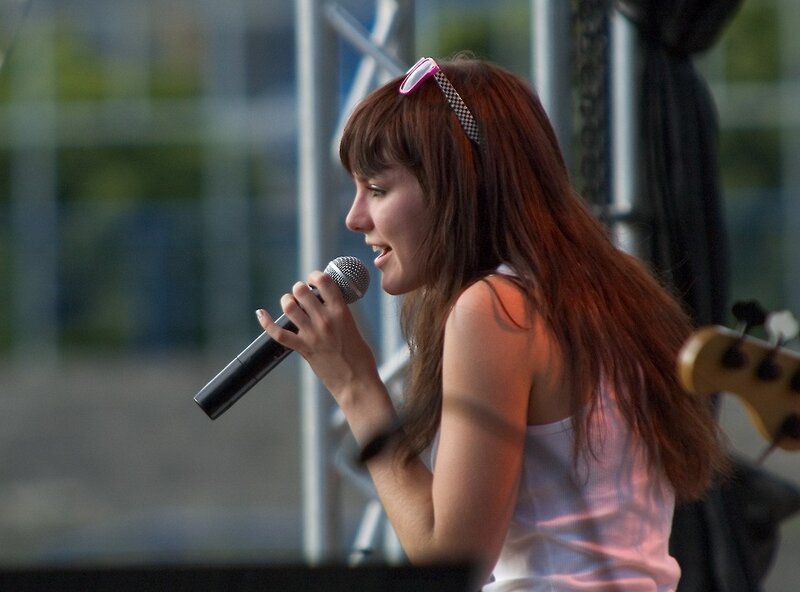 Woman Singing into Microphone — Brown, Lively, Afternoon, Photograph, Sunglasses