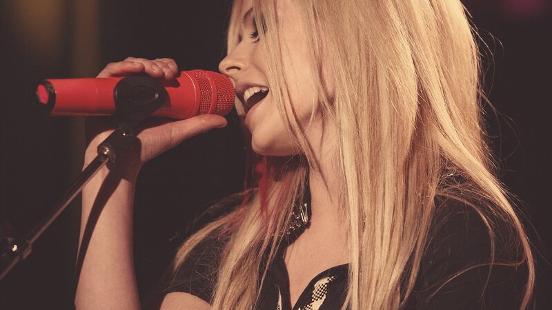 woman singing into red microphone