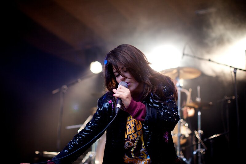 Woman Singing on Stage — Black, Dramatic, Night, Photograph, Microphone, Drum Kit, Stage Lights, White