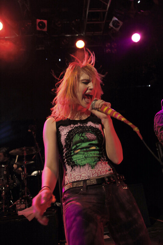 Woman Singing on Stage — Black, Energetic, Night, Photograph, Microphone, Drum Kit