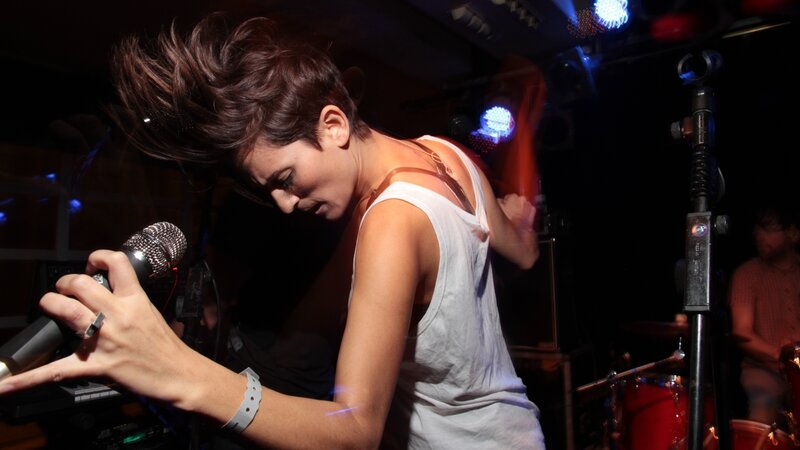 Woman Singing on Stage — Black, Energetic, Night, Photograph, Microphone, Drums