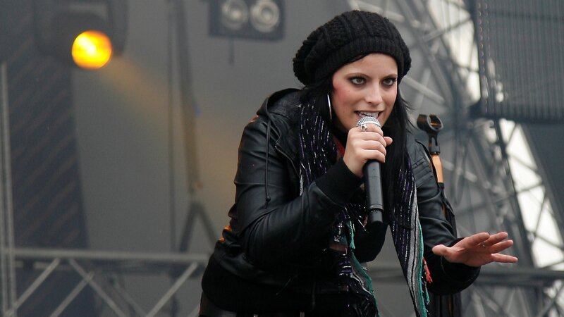 Woman Singing on Stage — Black, Energetic, Photograph, Microphone, Beanie
