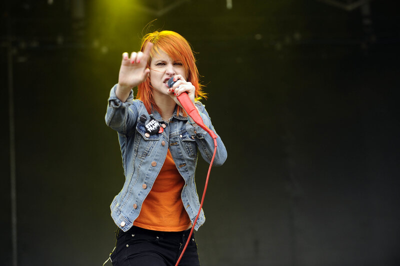 Woman Singing on Stage — Orange, Energetic, Photograph, Microphone, Denim Jacket, Stage Light