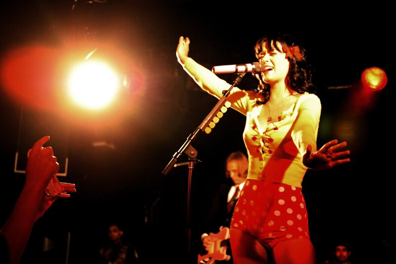Woman Singing on Stage — Red, Energetic, Night, Photograph, Microphone, Guitar, Spotlight