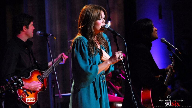 woman singing on stage with band
