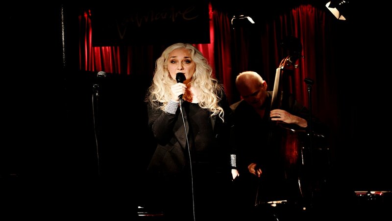 Woman singing on stage with bassist