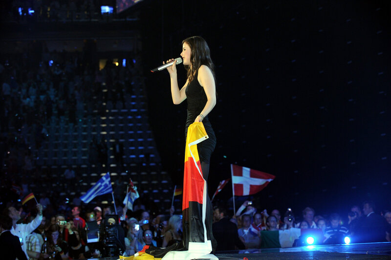 Woman singing on stage with flag