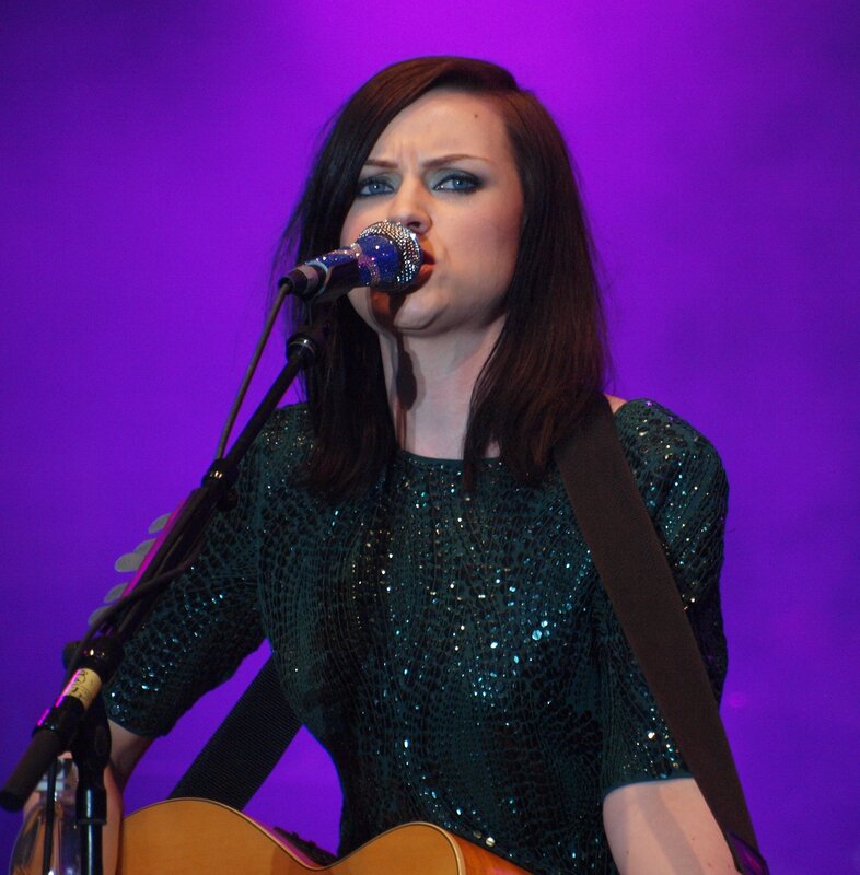 Woman singing with guitar on stage
