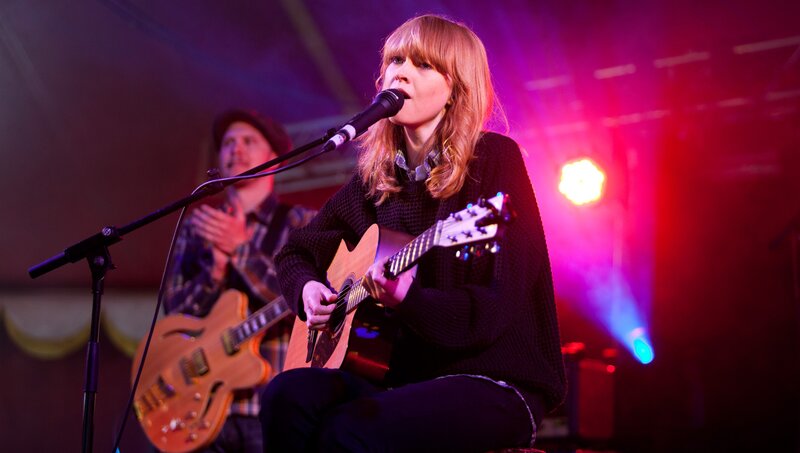 Woman singing with guitar on stage