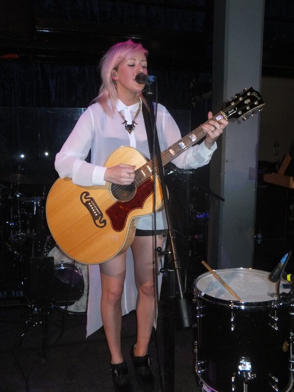 Woman singing with guitar on stage