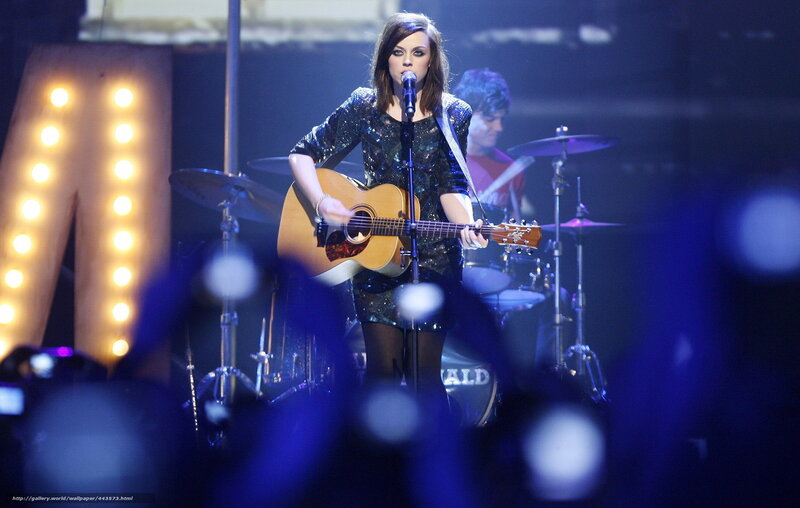 woman singing with guitar on stage