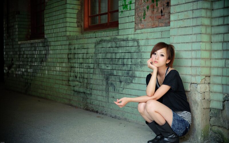 woman sitting against a brick wall