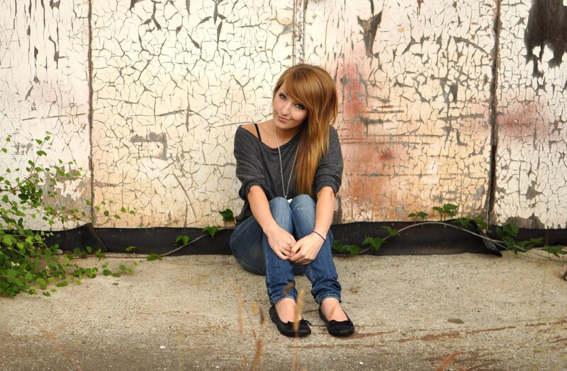 woman sitting against a cracked wall