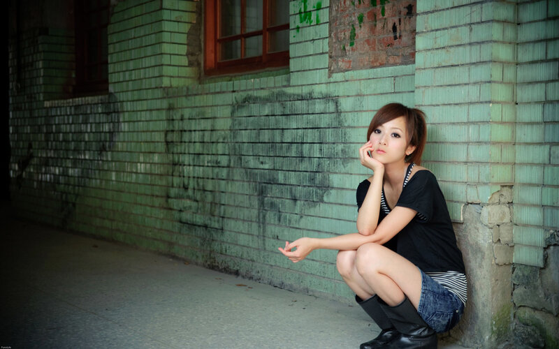 woman sitting against a green wall