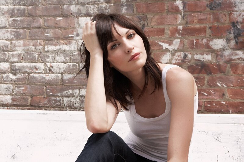 woman sitting against brick wall