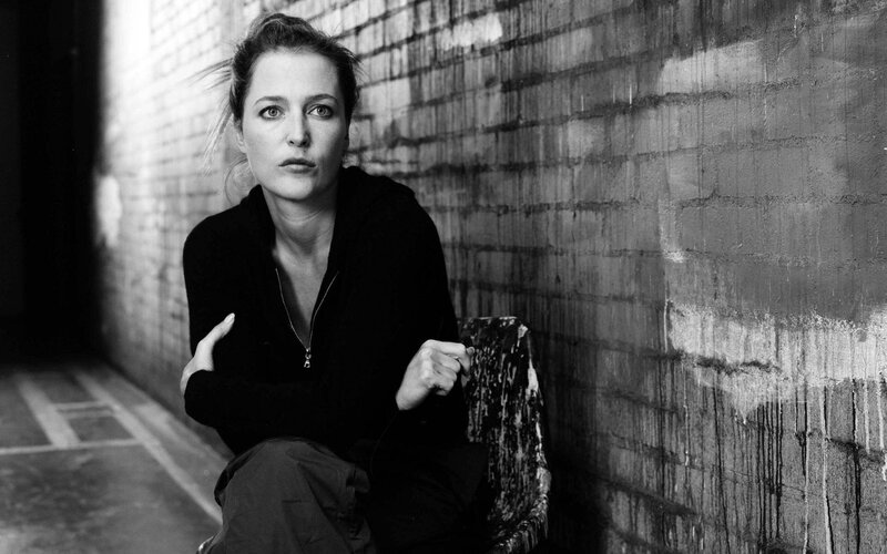 woman sitting against brick wall