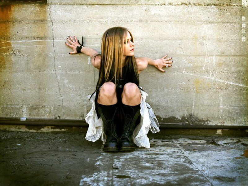 woman sitting against concrete wall