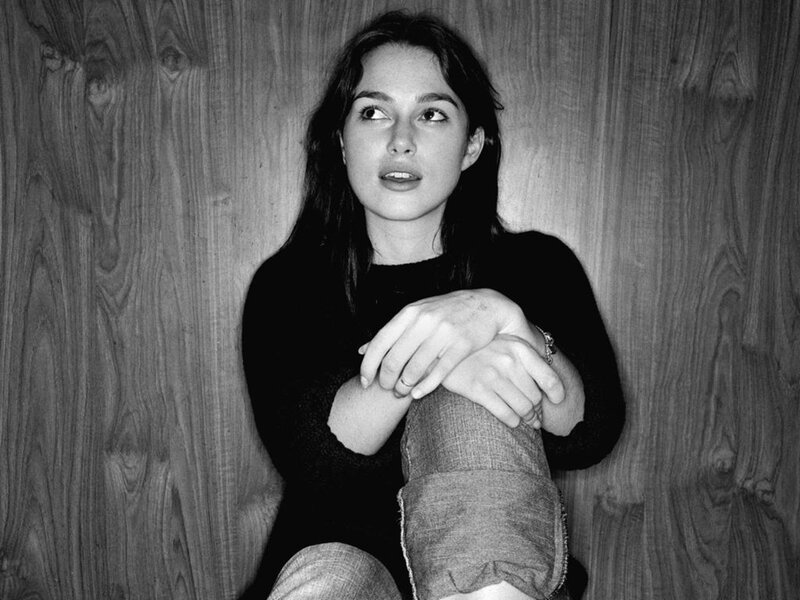 woman sitting against wood wall