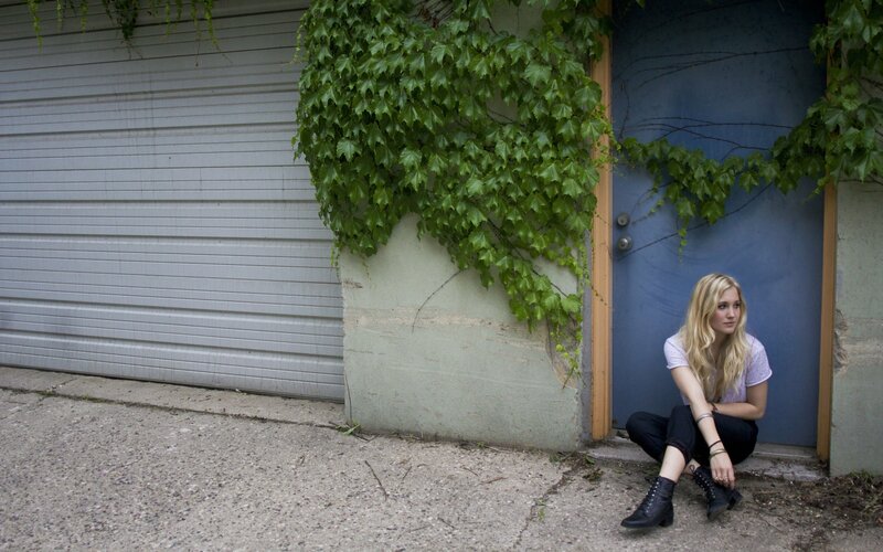 woman sitting by a blue door