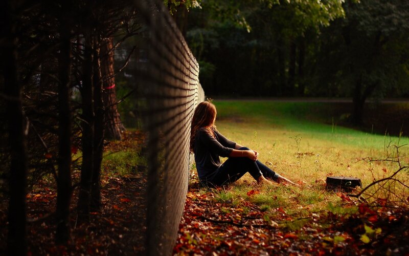 Woman sitting by a fence