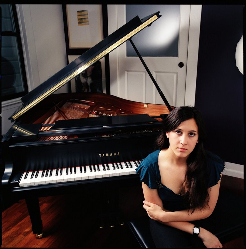 woman sitting by a grand piano