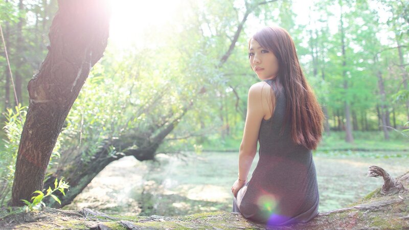 woman sitting by a pond