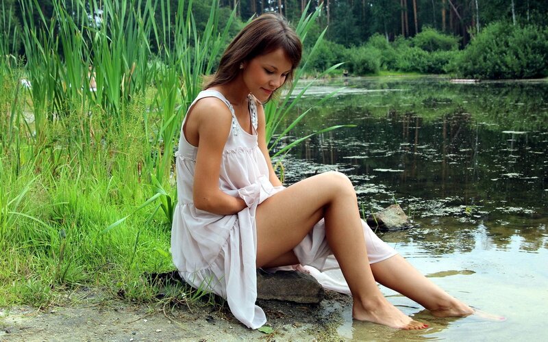 Woman sitting by a pond